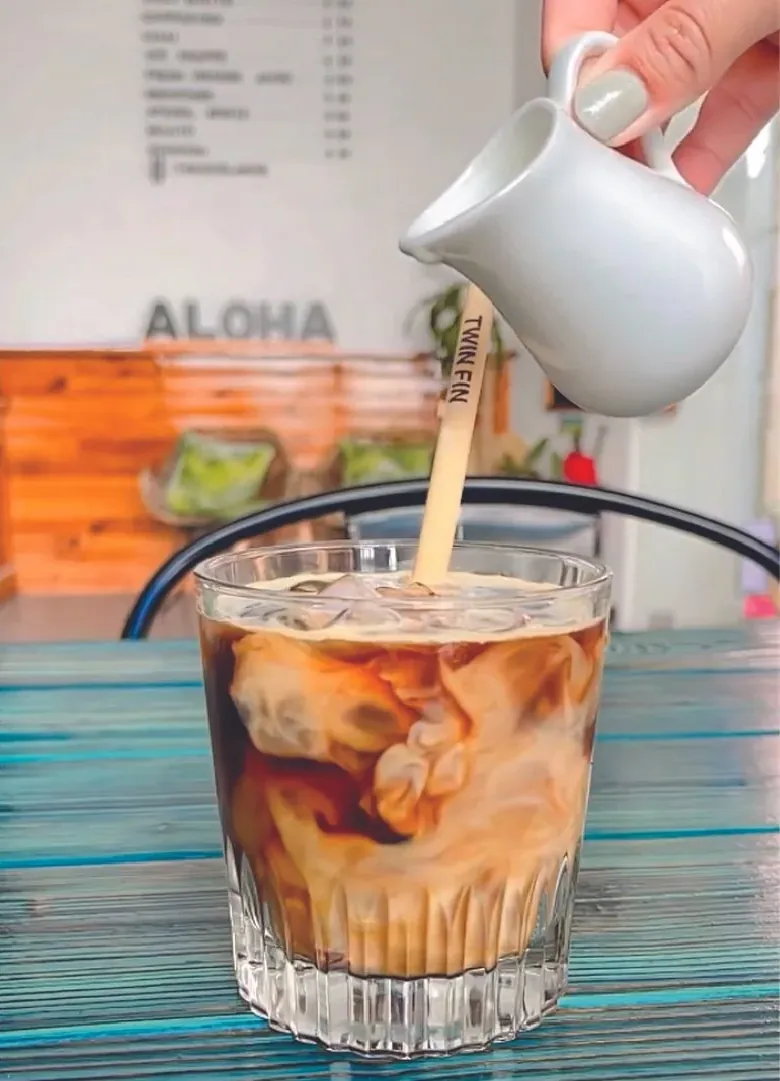 Milk poured into an iced coffee with a Twin Fin stirrer