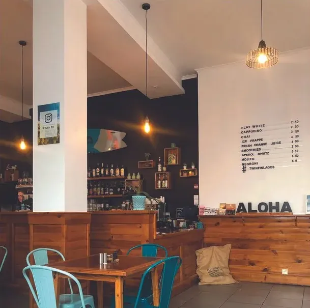 Inside Twin Fin: wooden bar, teal chairs and the ALOHA sign